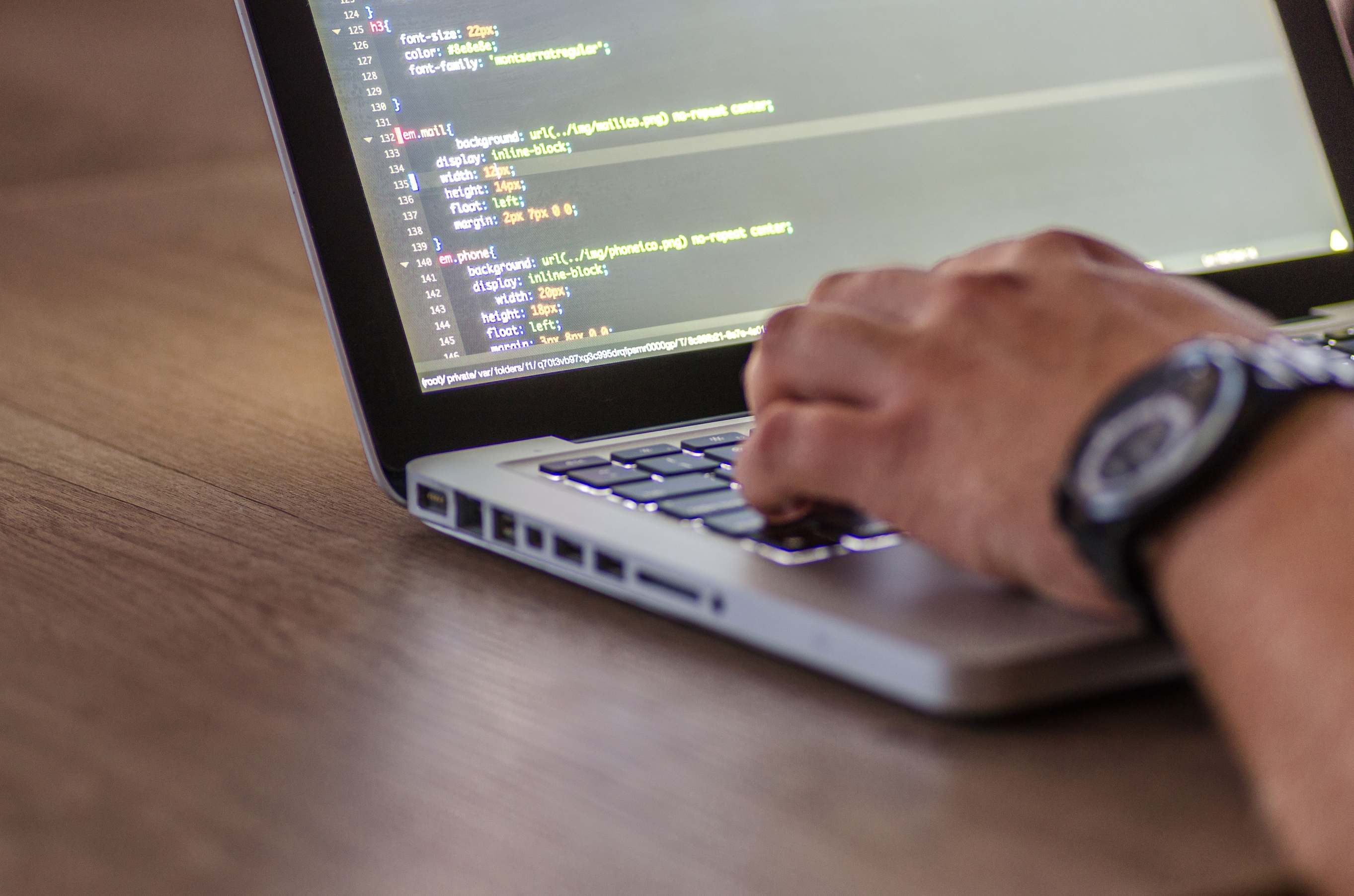Developer workstation with laptop for test automation work, close-up of person coding focusing on hands and screen