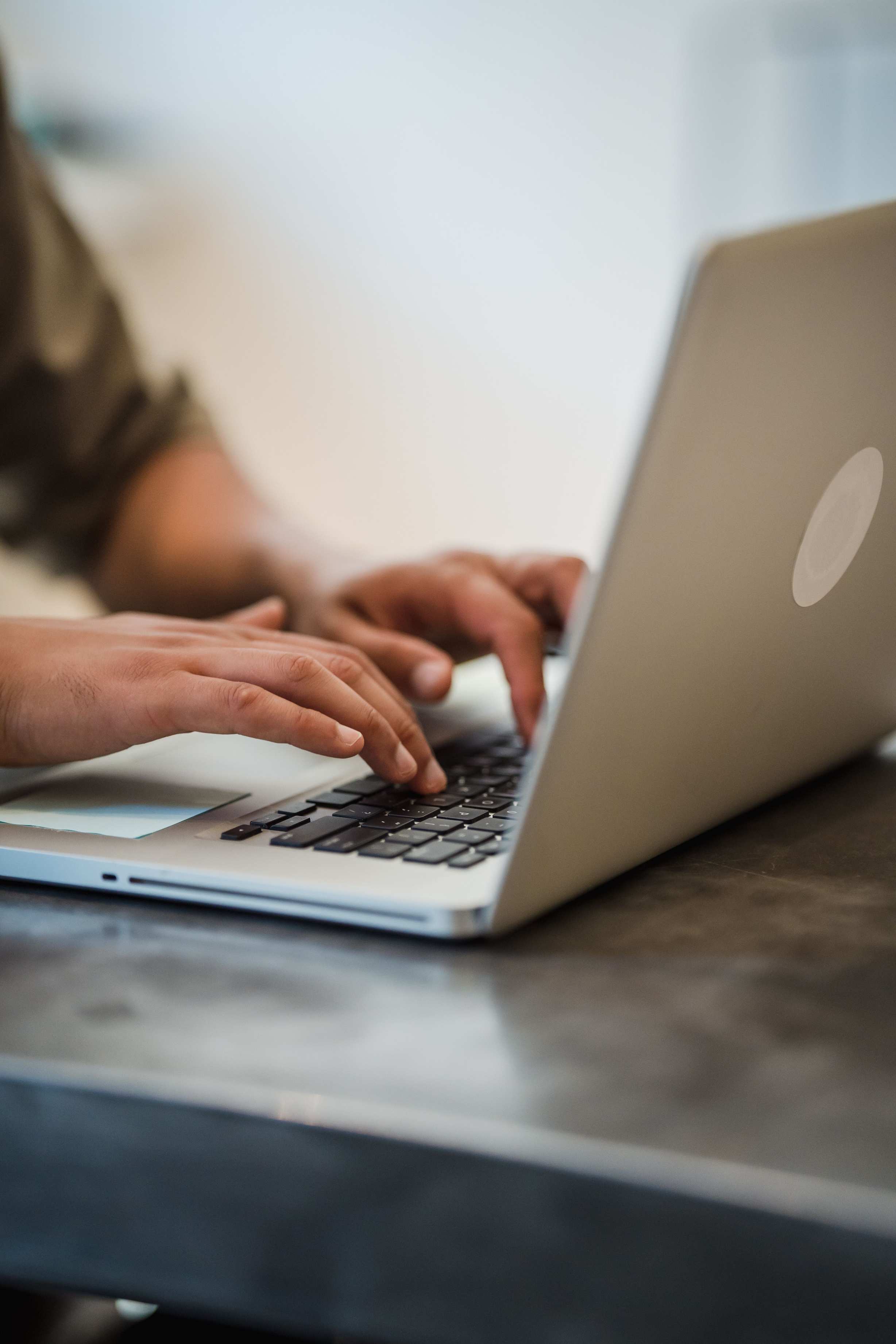 Hands typing on a laptop keyboard while writing automated tests, adult typing indoors focused on work